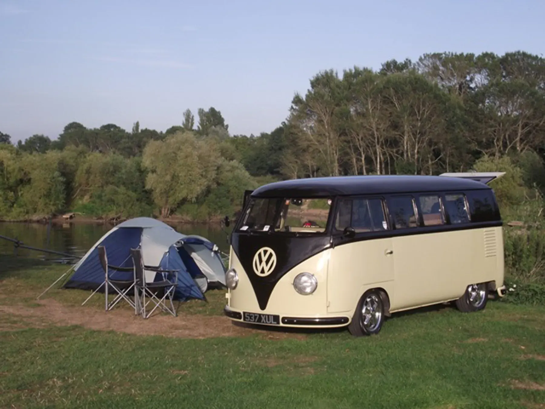 A campervan parked beside the riverside campsite